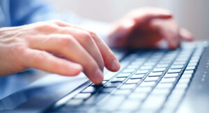 Close-up of hands typing on a laptop keyboard.